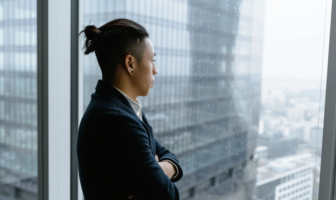  A professional person gazing out a window in quiet thought — microdosing for high achievers