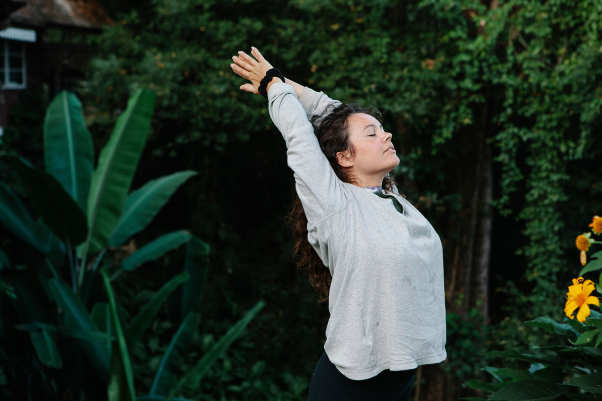Woman taking a deep breath outdoors, representing calm and self-awareness in a Medicine Box blog